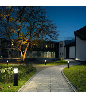 Several black cylindrical lawn lights line a garden pathway, providing ambient lighting during the evening.