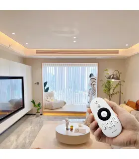 modern living room with ceiling light, a glass wall with white blinds, and a person holding a round white remote controller