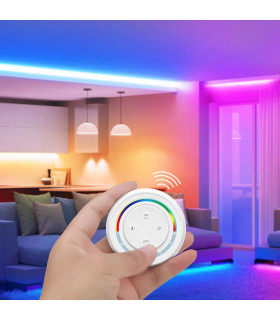 Hand holding a white remote with a colourful arc, adjusting vibrant lighting in a modern living room.