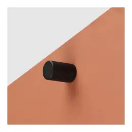 Matte black furniture knob on a copper background.