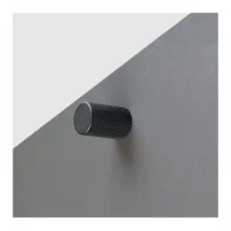 Matte black furniture knob on a grey background.