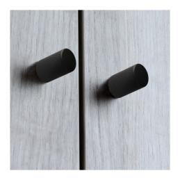 Two matte black furniture knobs on grey cabinet doors.