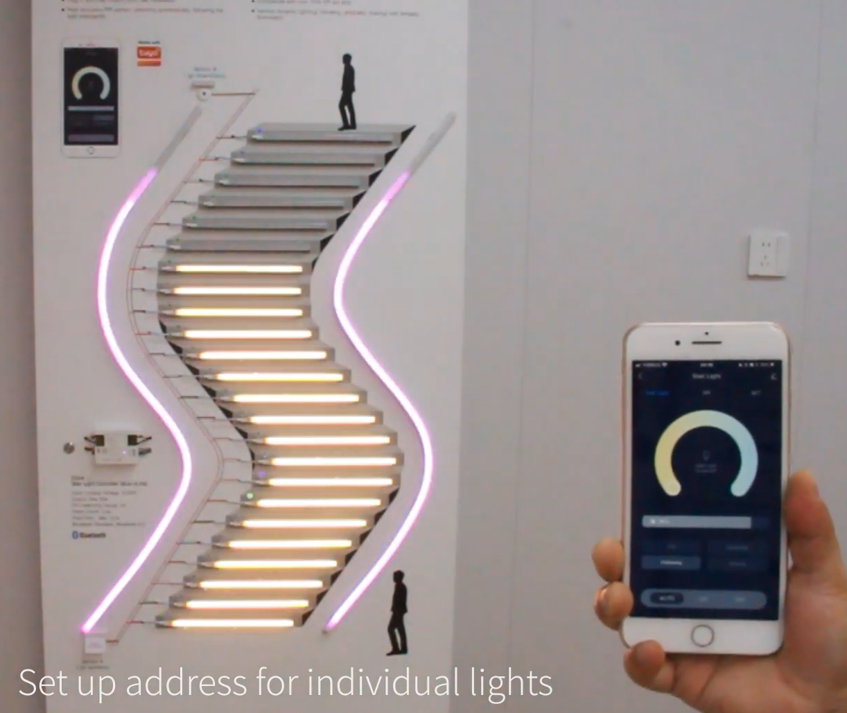 Demonstration board showing illuminated staircase with dual-white and RGB LED strips, controlled via smartphone app for individual step light addressing.